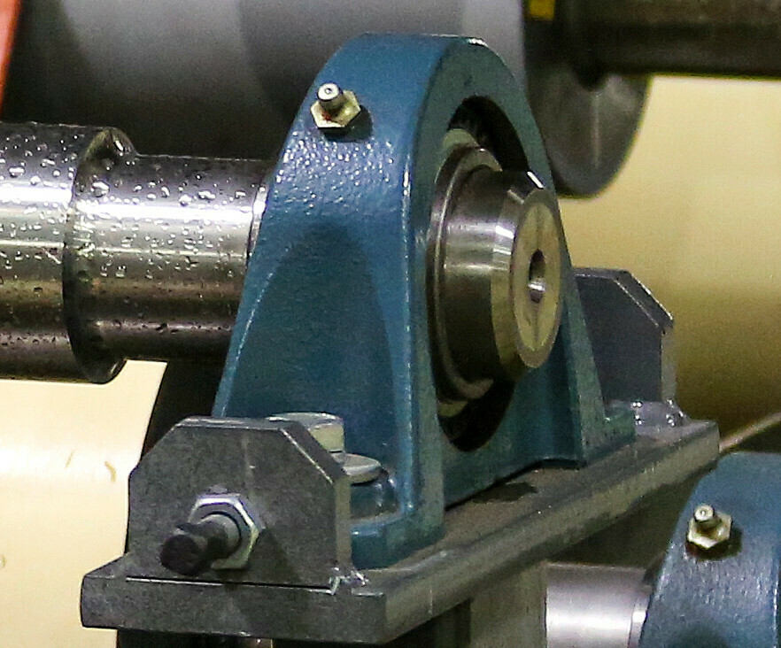 A heavy-duty mounted bearing and ball housing assembly secured to a metal machine frame.
